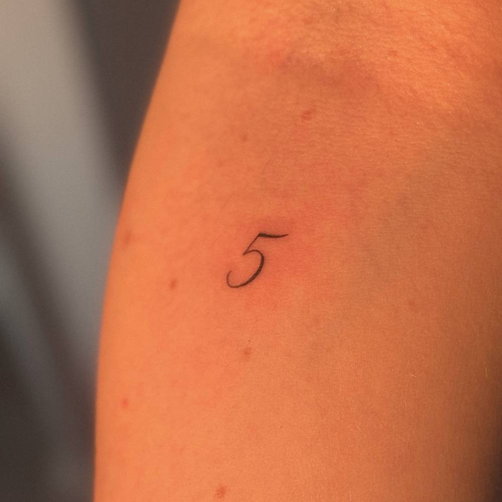 Little number "5" tattoo located on the inner forearm.