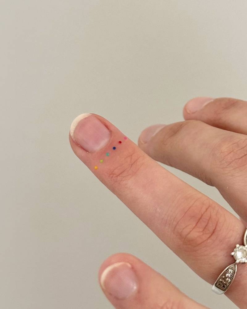 Tiny colorful dots tattooed on the finger.