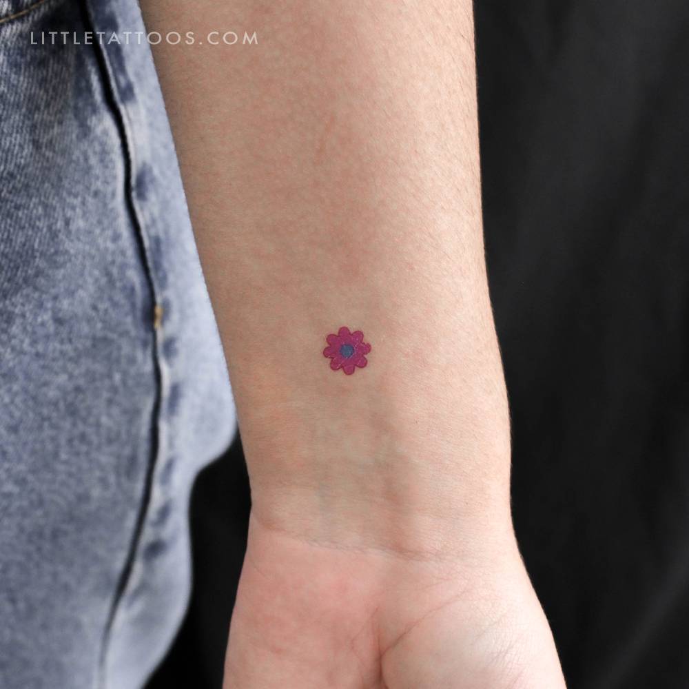 Tiny minimalistic pink flower temporary tattoo located on the wrist.