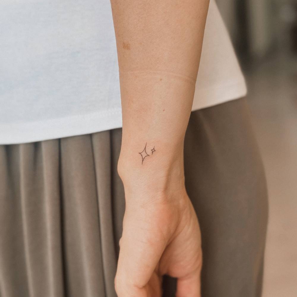 Minimalistic style sparkling stars tattoo located on the wrist.