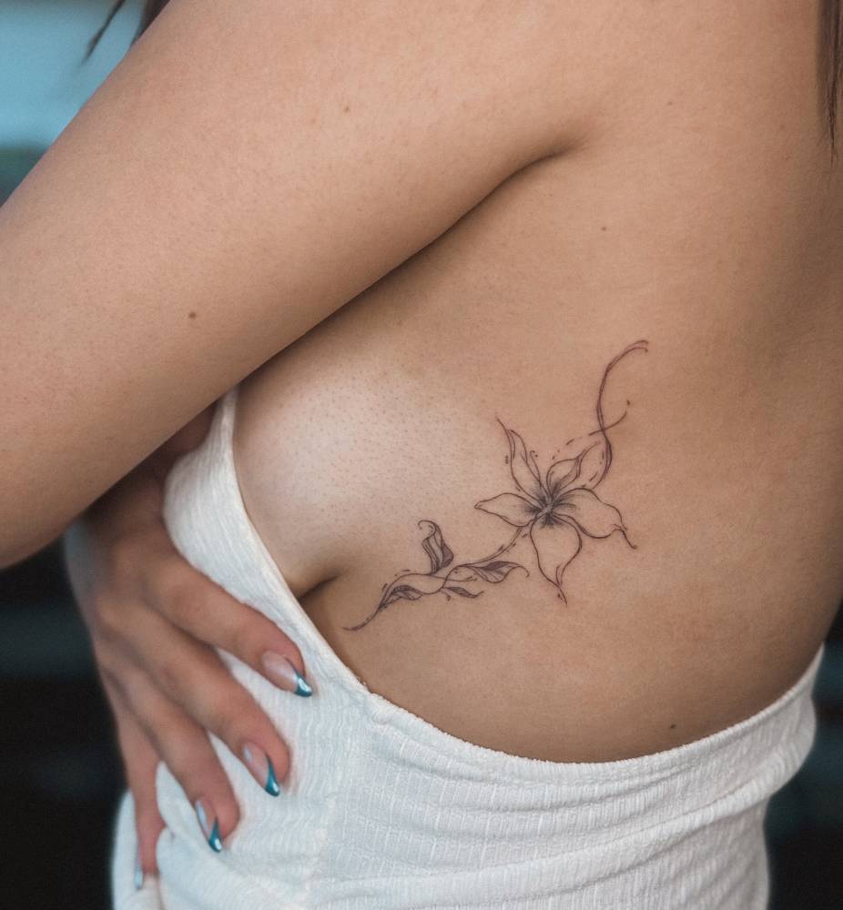Illustrative style lily flower tatoo located on the side boob.