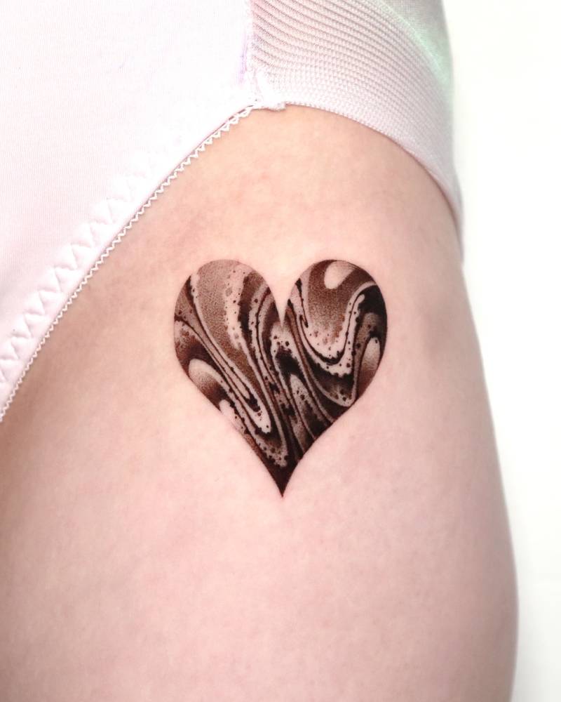 Abstract heart tattoo located on the hip, done in blackwork style.