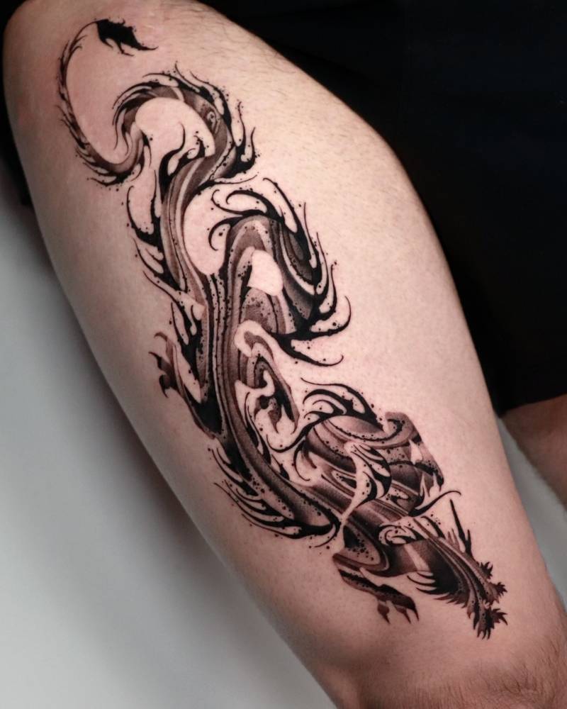 Abstract dragon tattoo in blackwork style located on the thigh.