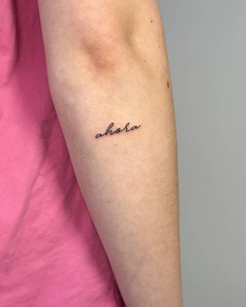 Lettering tattoo of the word "ahora" located on the forearm.