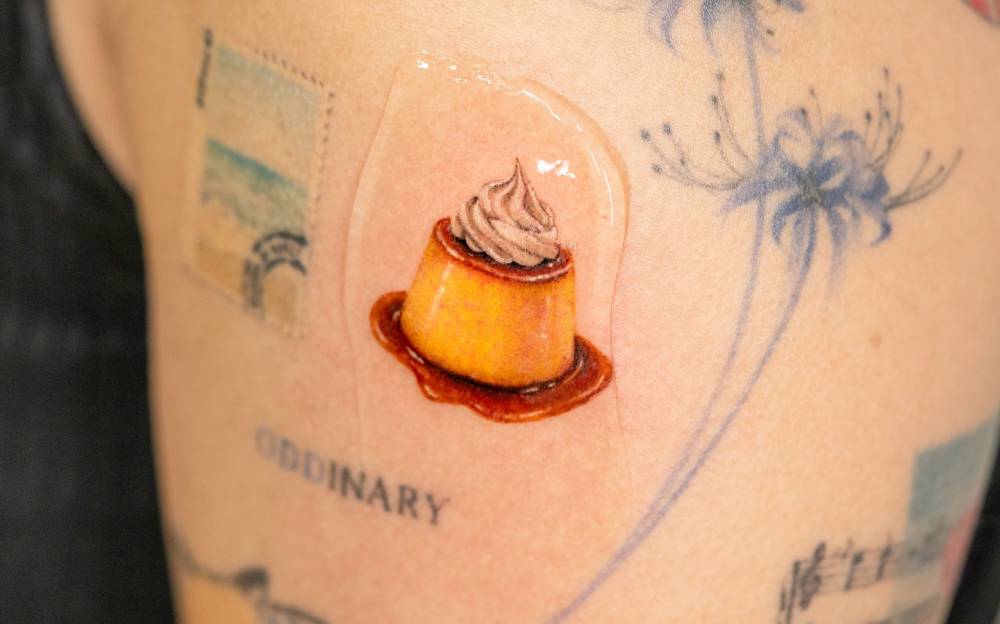 Micro-realistic style pudding tattoo located on the upper arm.