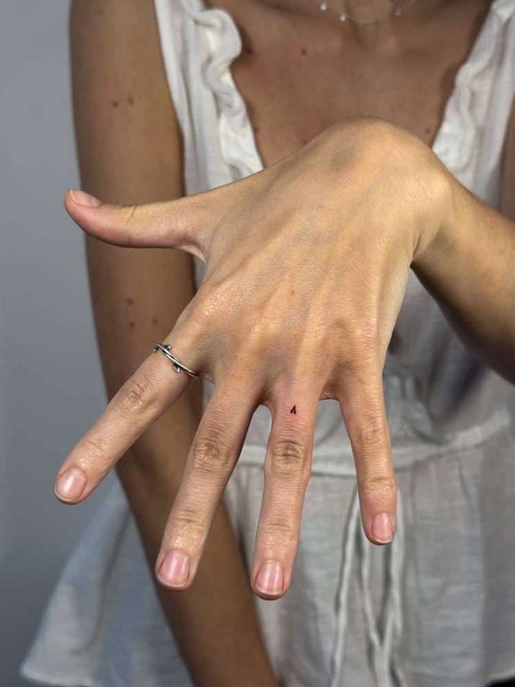 Tiny minimalistic heart tattoo located on the finger.
