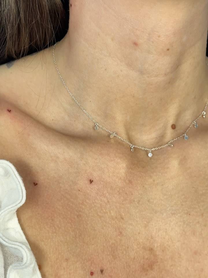 Little heart freckles tattooed on the collarbone, minimalistic style.