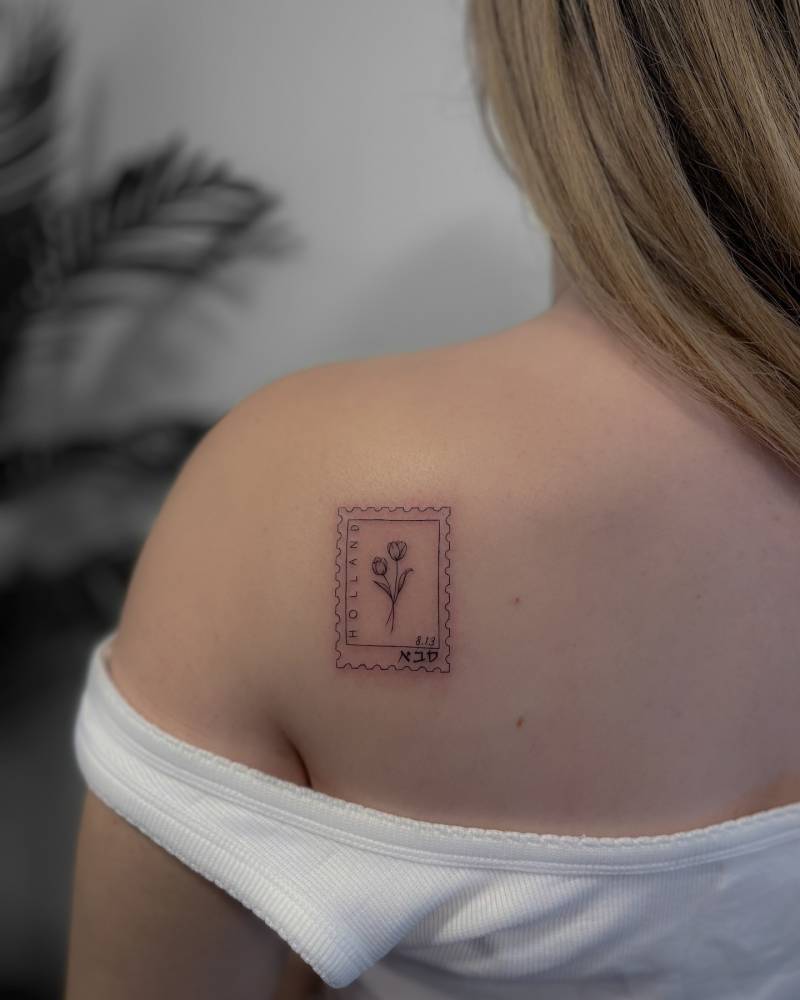 Fine line style tulip stamp tattoo located on the shoulder blade.