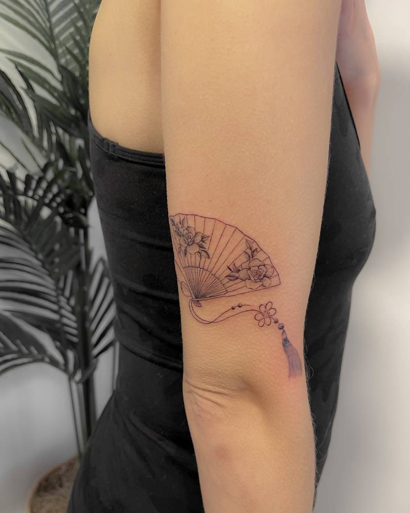 Hand fan tattoo done on the tricep, illustrative style.