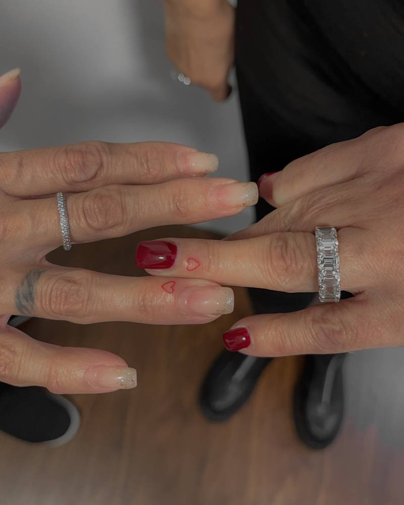 Tiny matching red heart tattoo for mother and daughter.