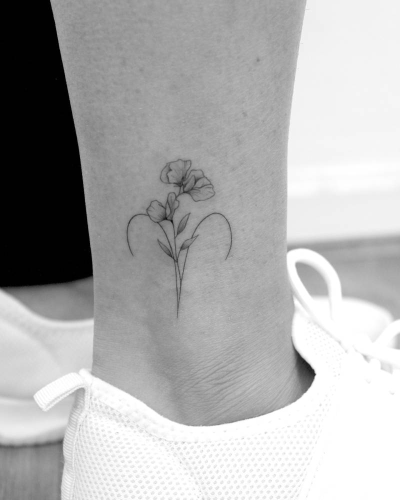 Sweet peas and Aries zodiac symbol tattooed on the ankle.