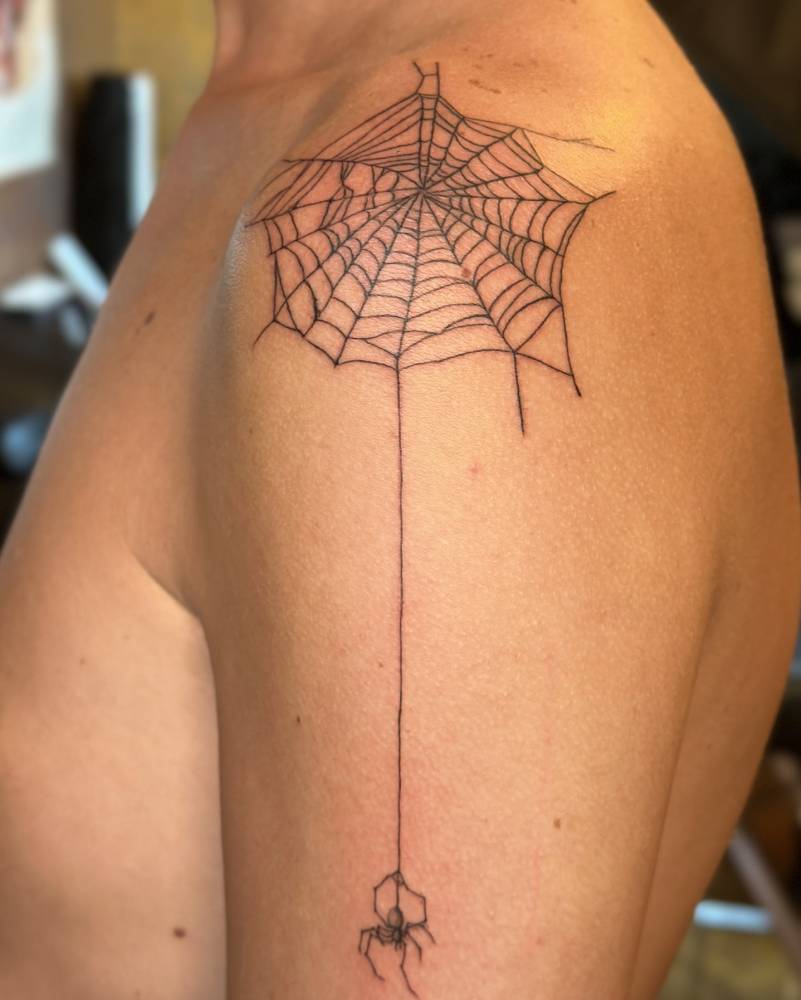 Spider and web tattoo located on the upper arm and shoulder.