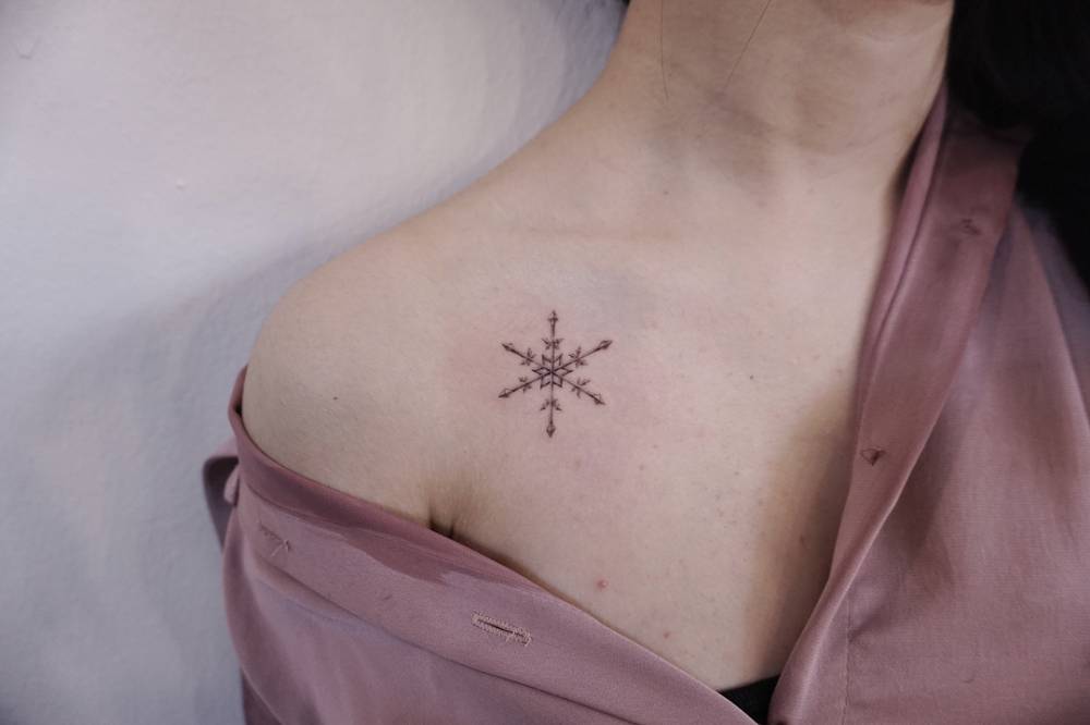 Snowflake tattoo located on the collarbone.