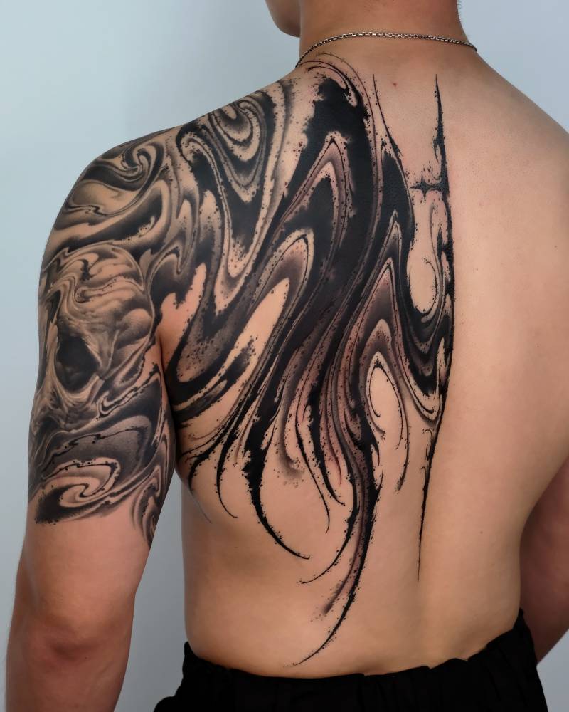 Abstract wing tattoo in blackwork style located on the back.