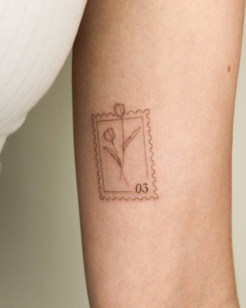 Tulip stamp tattoo in fine line style placed on the inner arm.