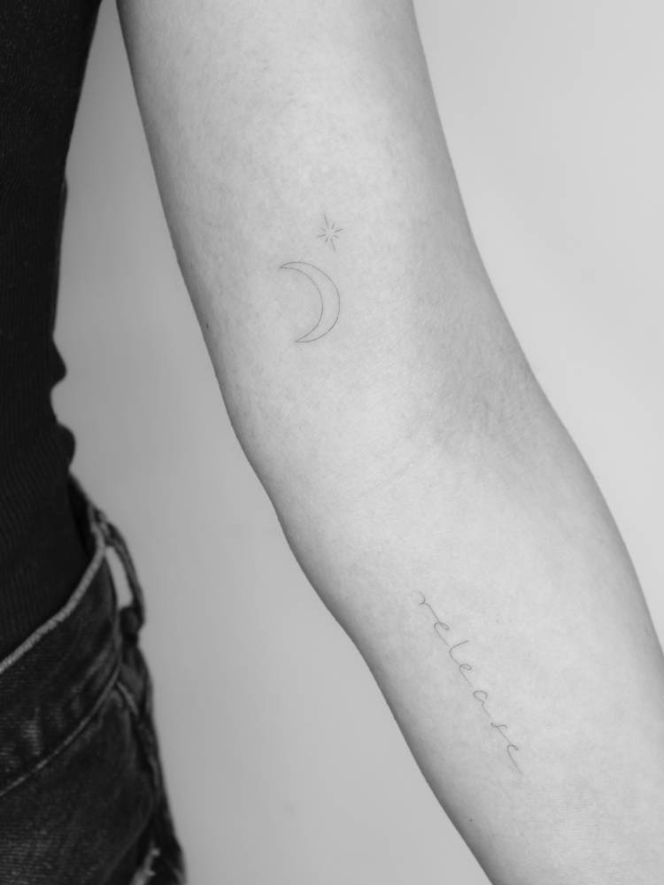Star, moon and word "release" tattooed on the arm.