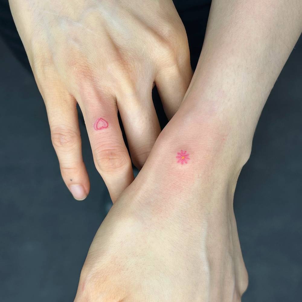 Hand poked flower and heart tattoos in minimalistic style.