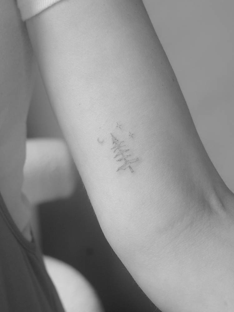 Little pine tree tattoo in fine line style placed on the inner arm.