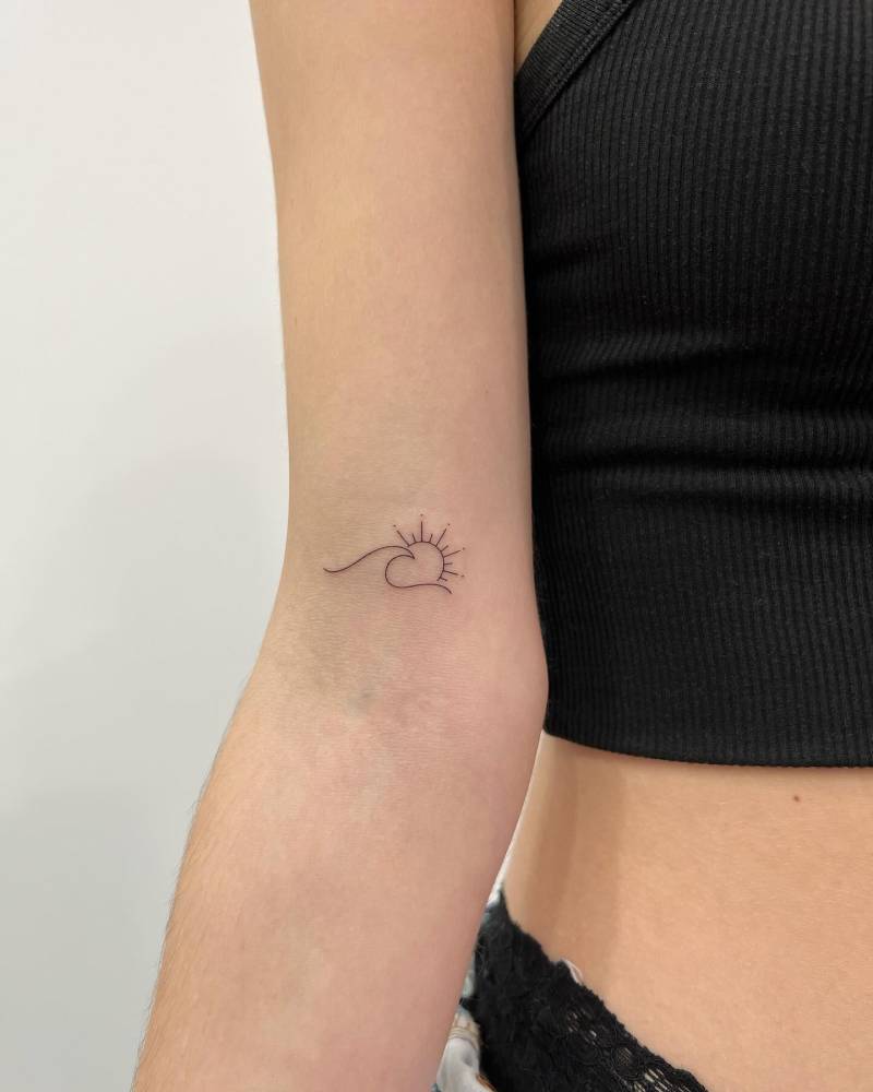 Fine line style sun and wave tattoo located on the inner arm.