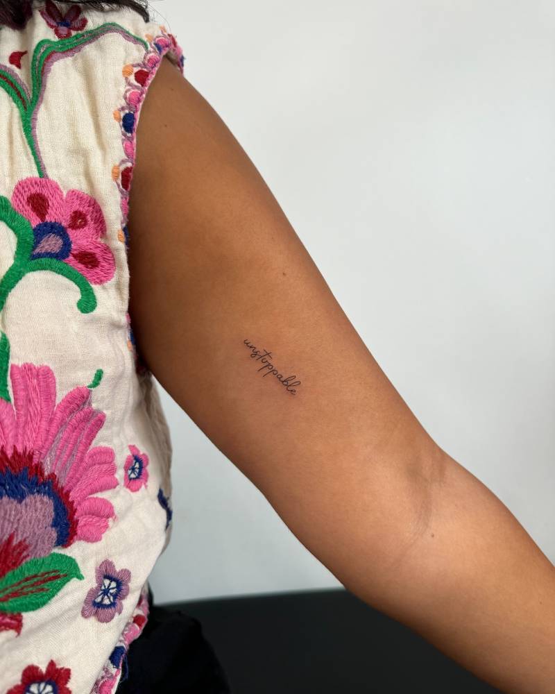Handwritten font word "unstoppable" tattooed on the inner arm.