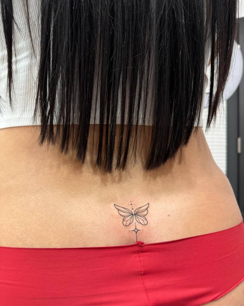 Fine line style butterfly tattoo placed on the lower back.