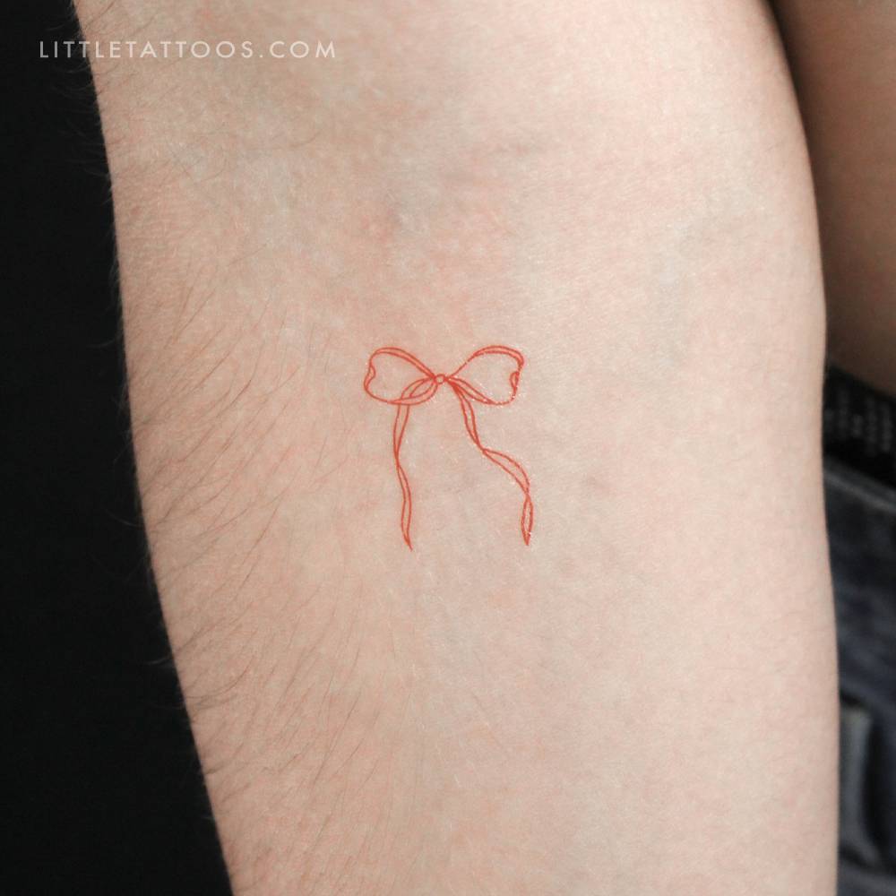 Red ribbon bow temporary tattoo located on the inner forearm.