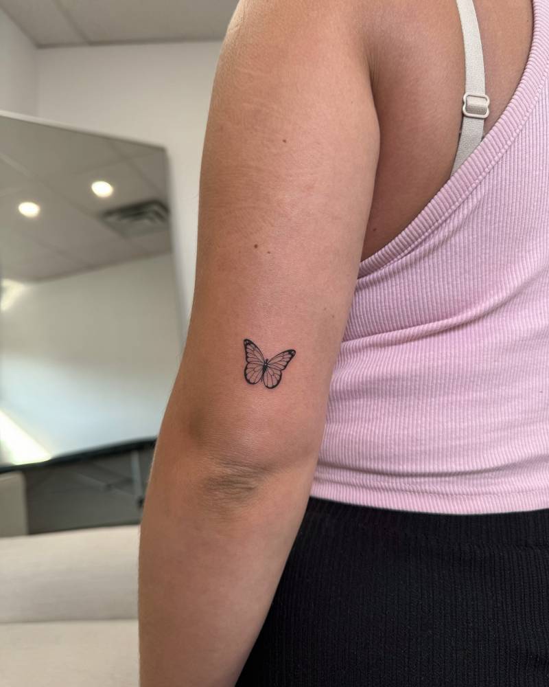 Little butterfly tattoo in fine line style done on the tricep.