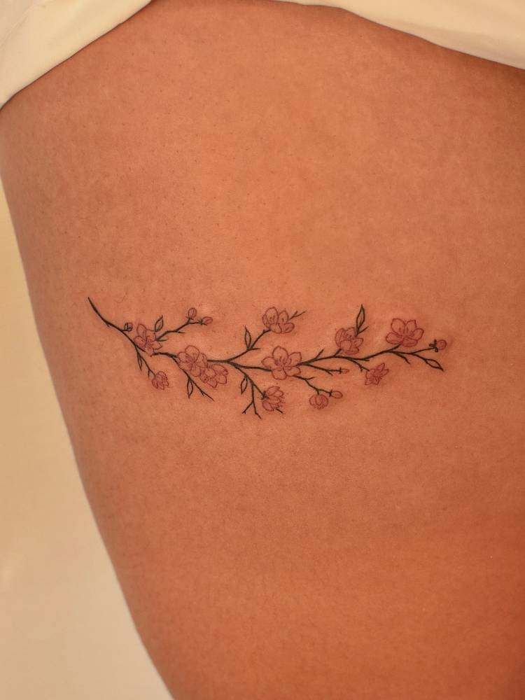 Cherry blossom tattoo in fine line style located on the thigh.