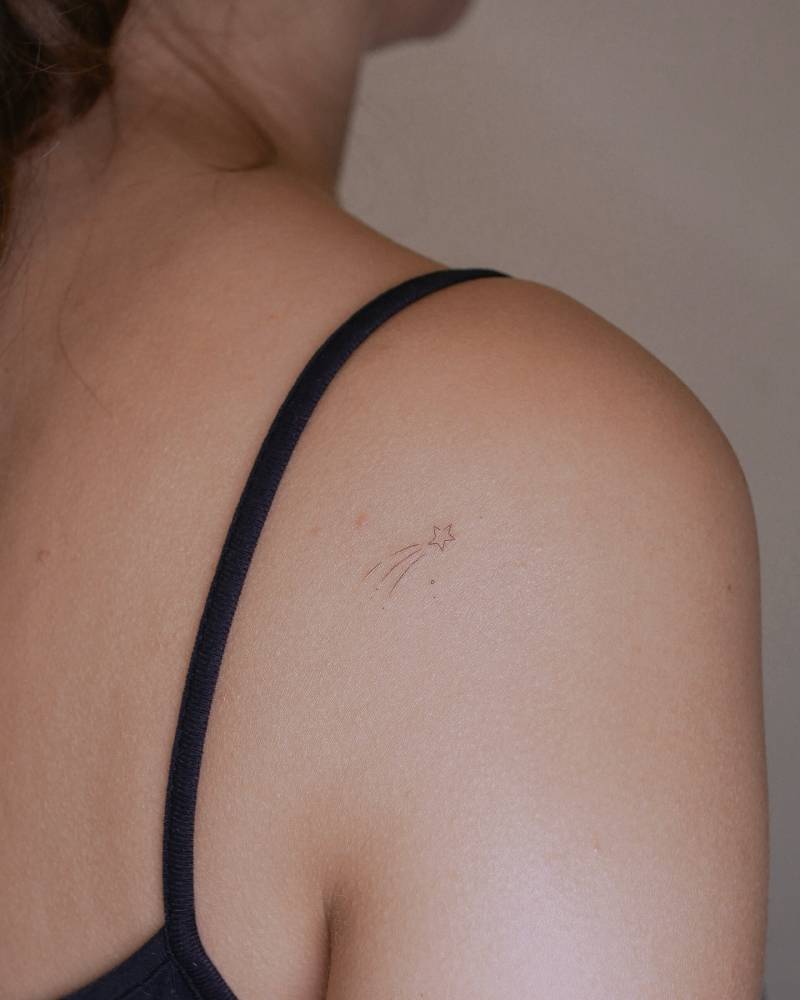 Little minimalistic shooting star tattoo located on the shoulder blade.