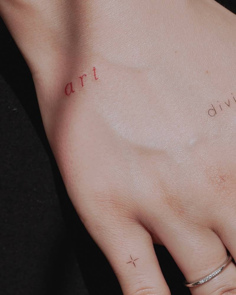 Word "art" in red ink tattooed on the hand.