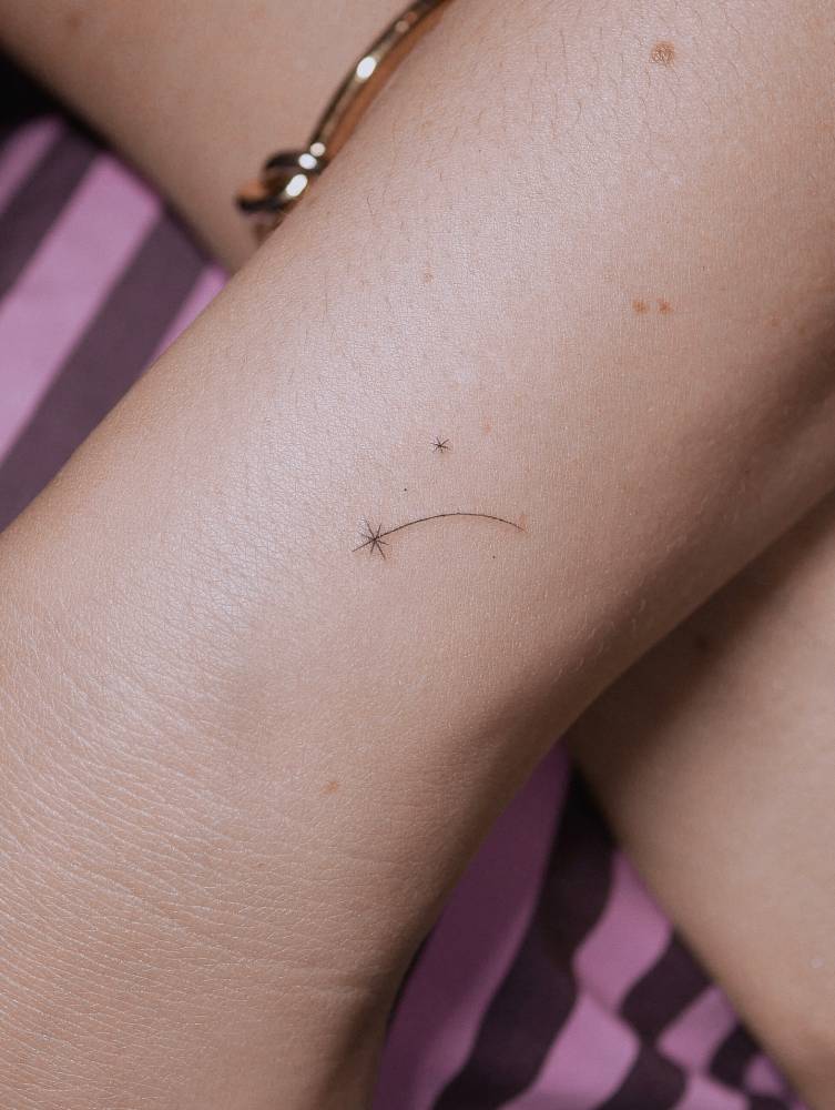 Tiny minimalistic shooting star tattoo located on the wrist.