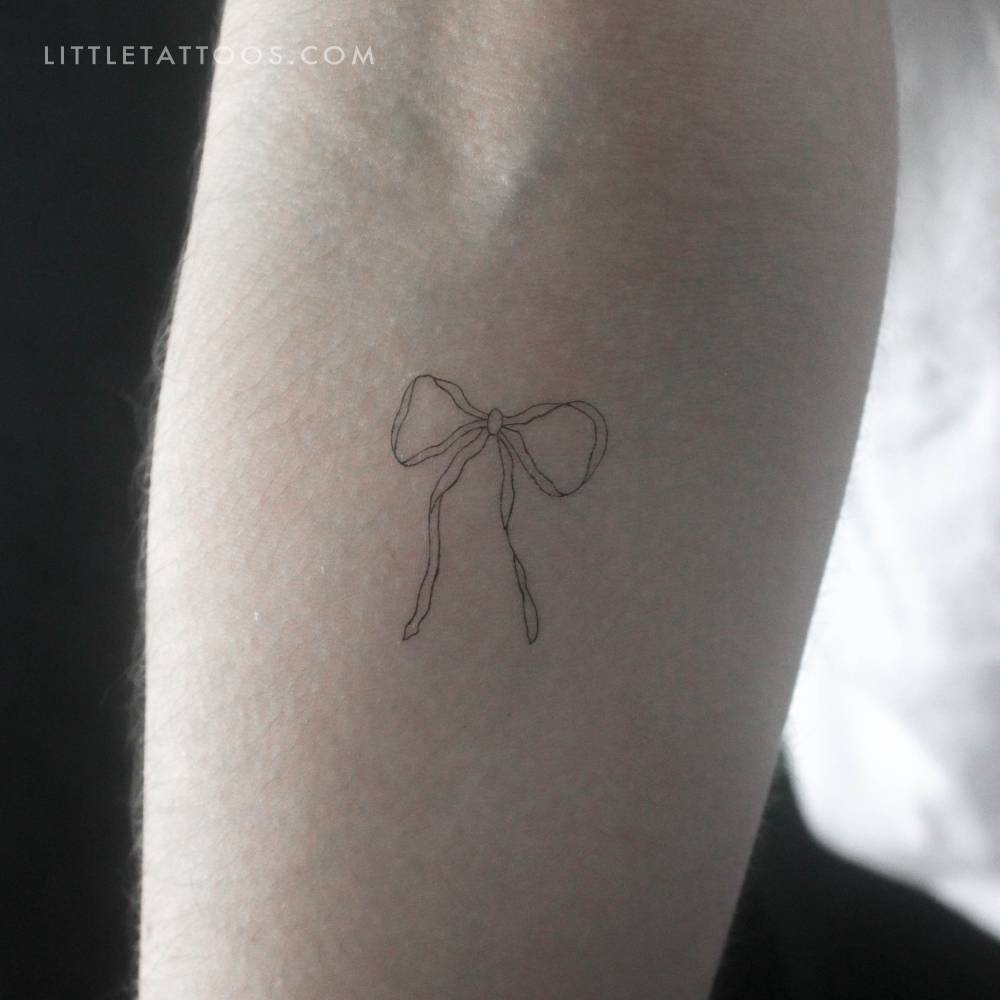 Fine line style ribbon bow temporary tattoo located on the inner forearm.