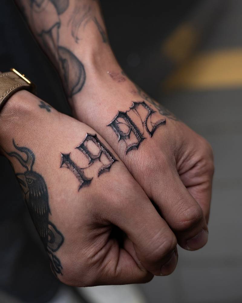 Individual matching "1992" lettering tattoo in gothic font.