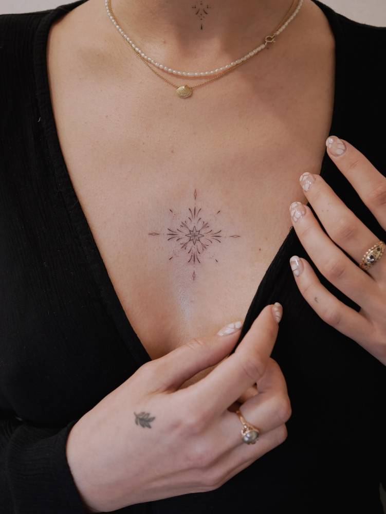 Ornamental tattoo in fine line style located on the chest.