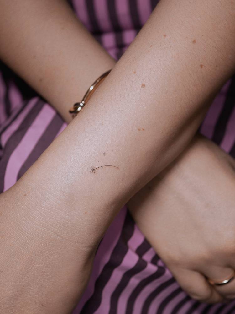 Tiny shooting star tattoo in minimalistic style located on the wrist.