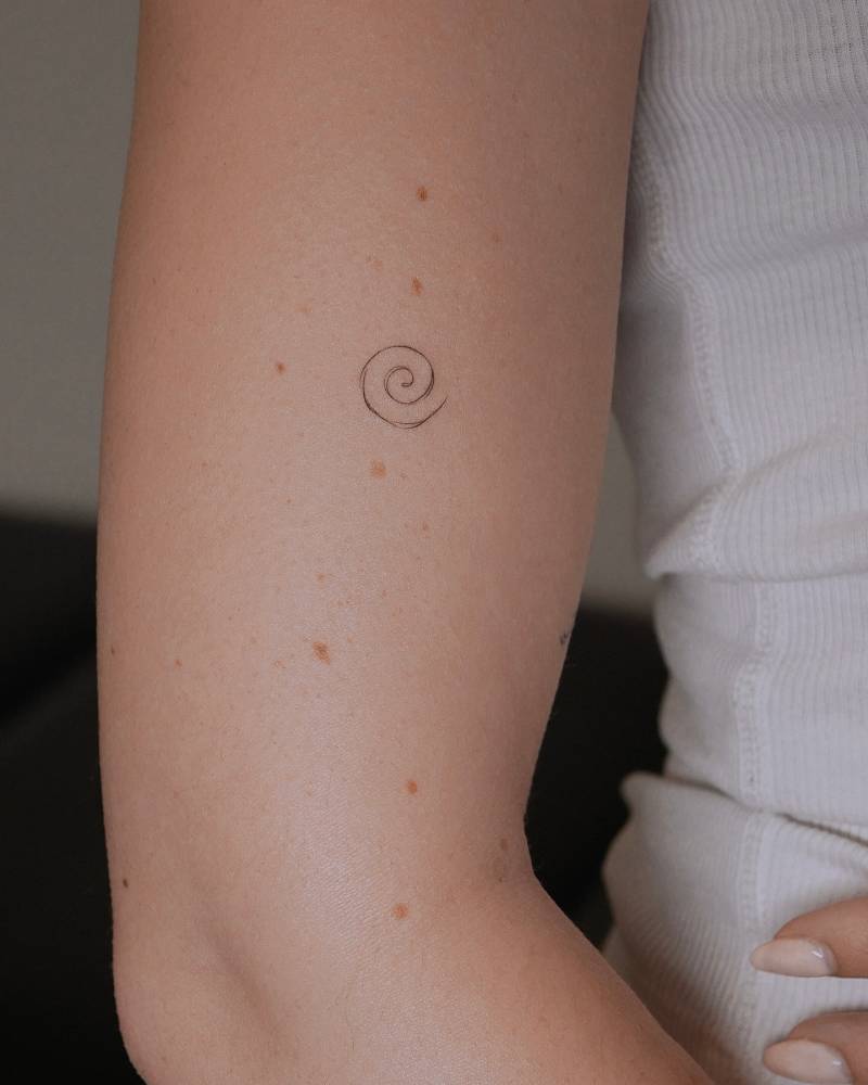 Little spiral tattoo done on the upper arm, minimalistic style.