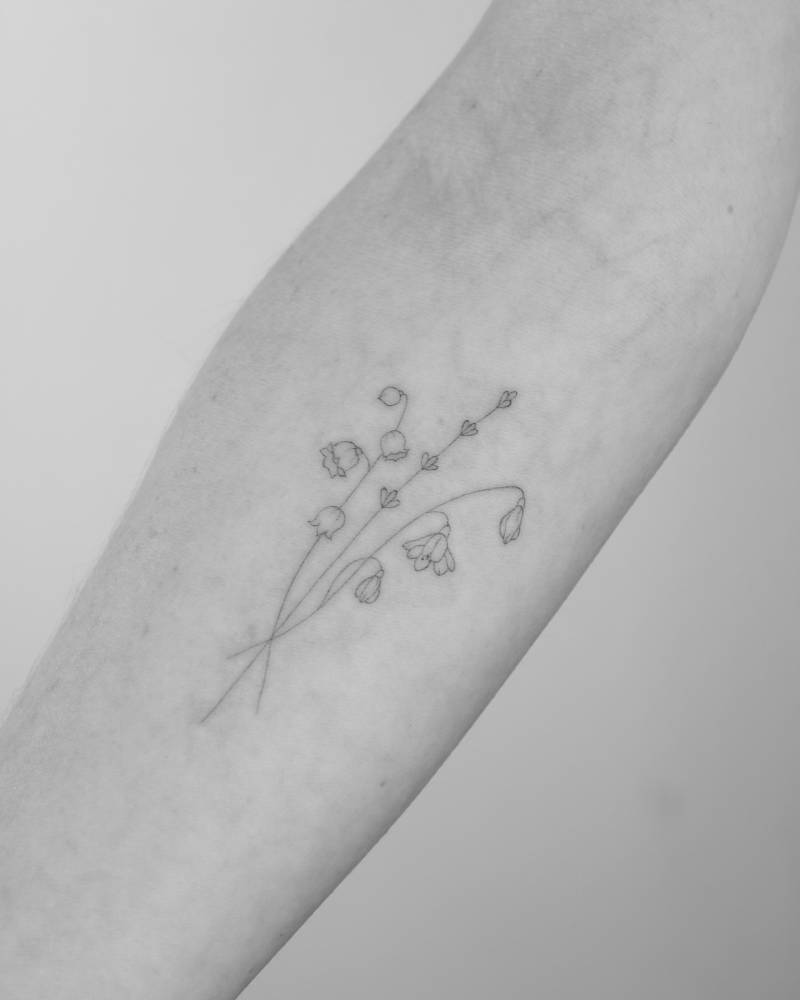 Flower bouquet tattoo in fine line style located on the inner forearm.