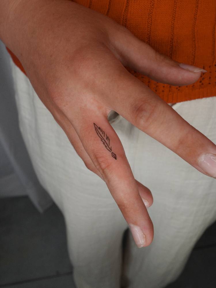 Minimalistic style tiny quill tattoo placed on the finger.