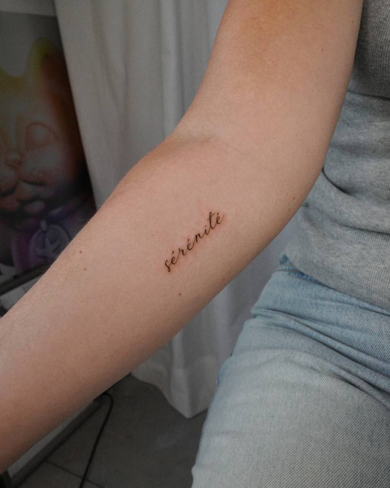 "Sérénité" lettering tattoo handwritten on the inner forearm.