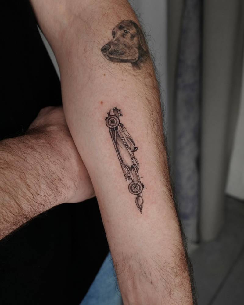 Illustrative style Formula 1 cat tattooed on the inner forearm.