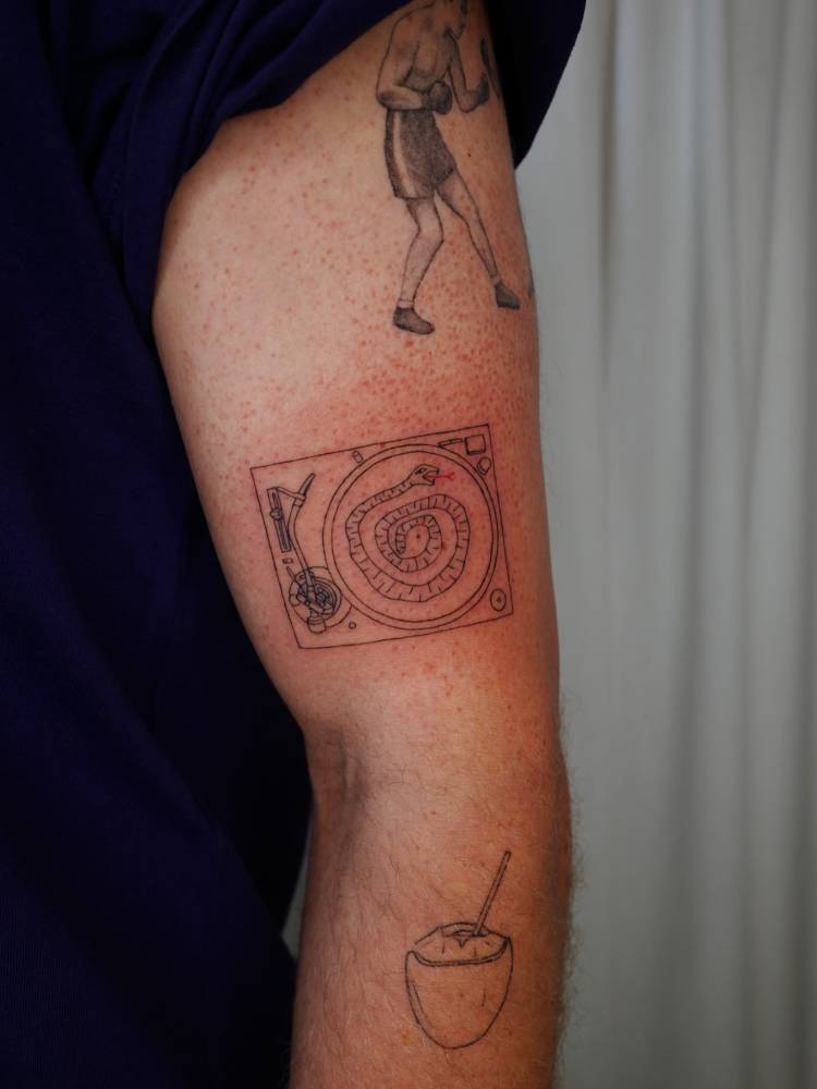 Snake turntable tattoo located on the upper arm, done in fine line style.