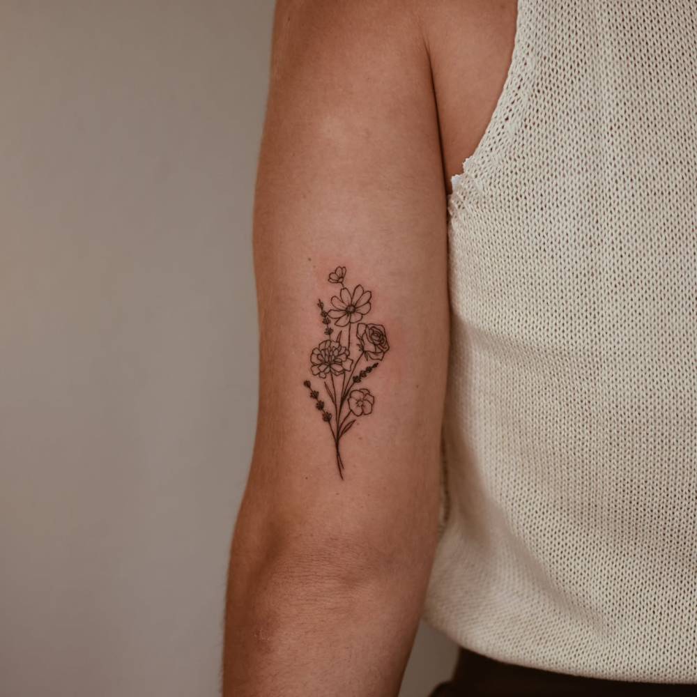 Flower bouquet tattoo in illustrative style located on the tricep.