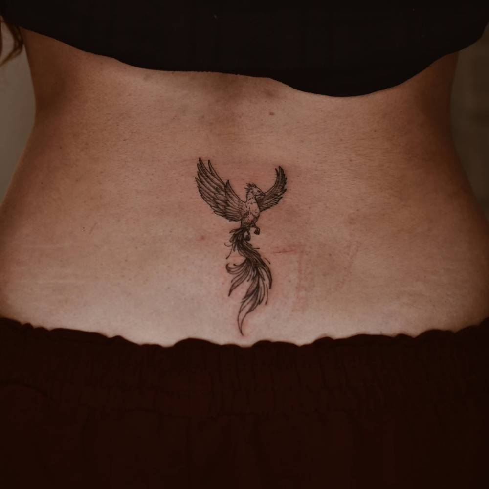 Illustrative style phoenix tattoo located on the lower back.