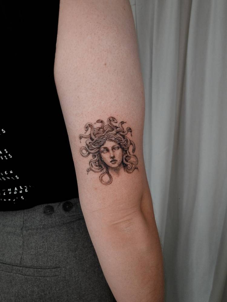 Classical style Medusa portrait tattoo located on the tricep.