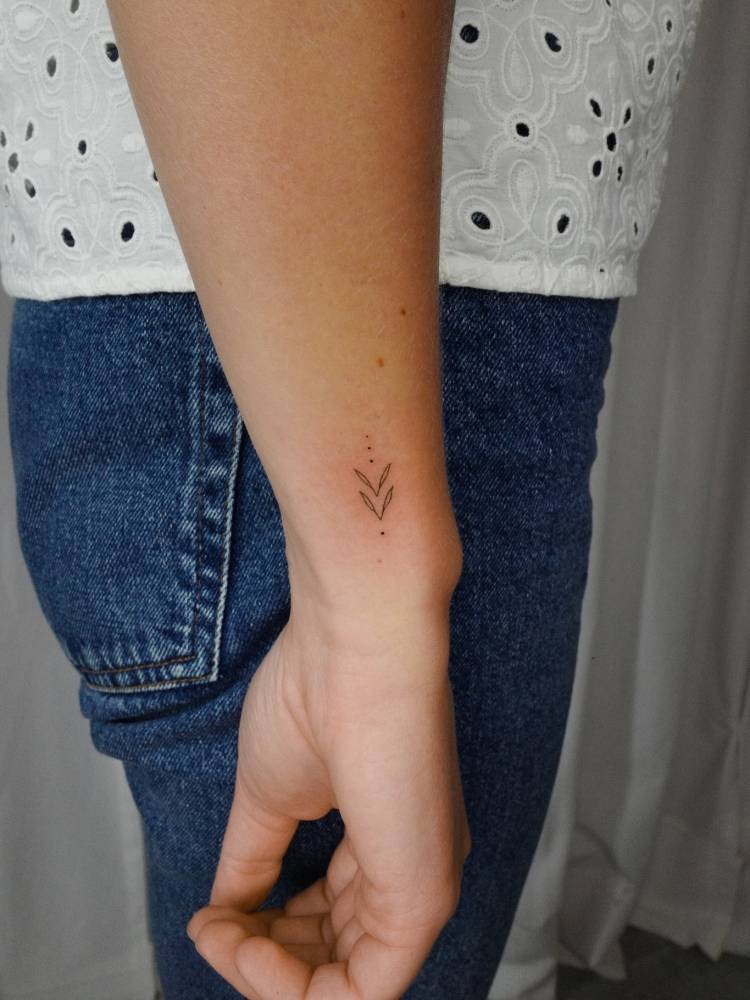 Fine line style ornamental tattoo located on the wrist.