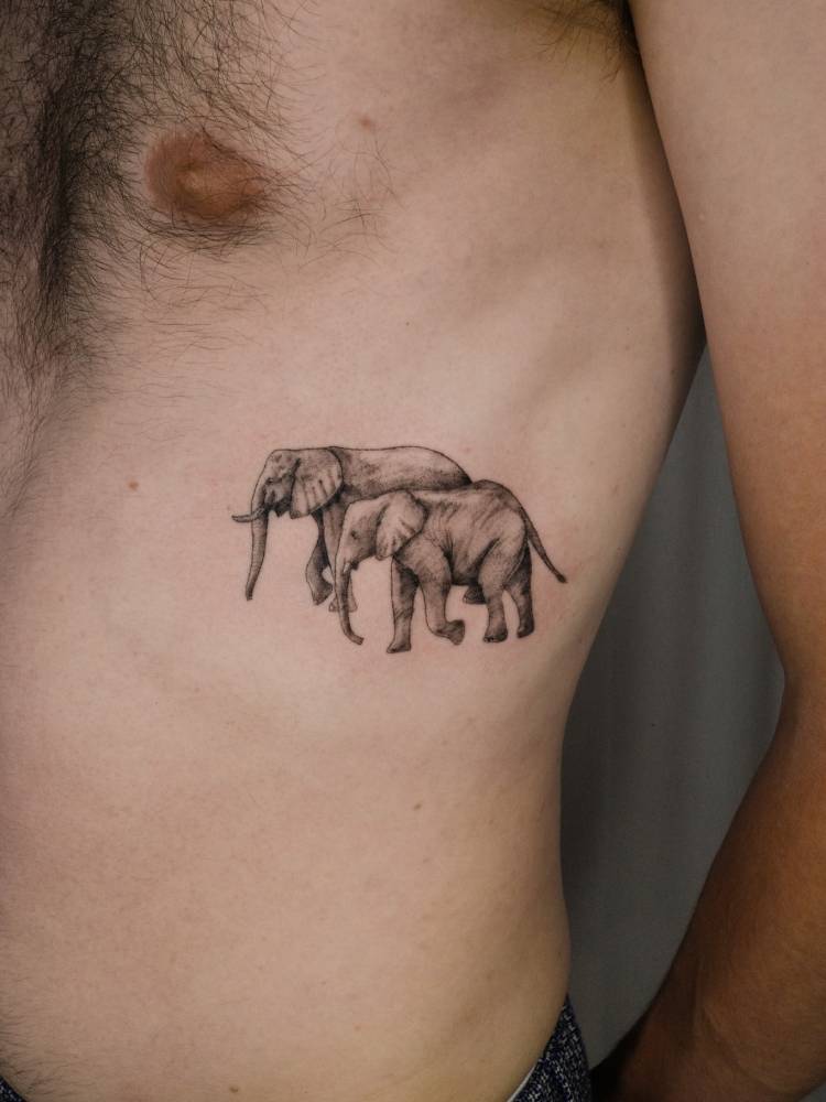 Micro-realistic style elephant couple tattoo located on the rib.