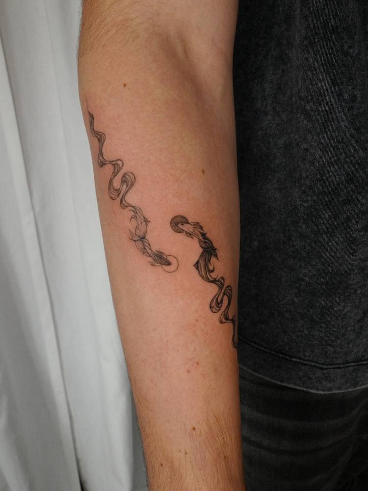 Two opposite fish tattoo in illustrative style located on the forearm.