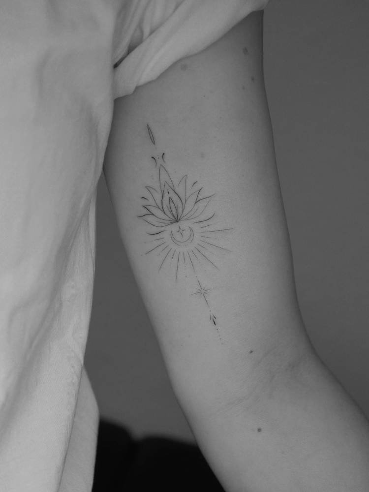 Ornamental lotus, sun and moon tattoo located on the inner arm.