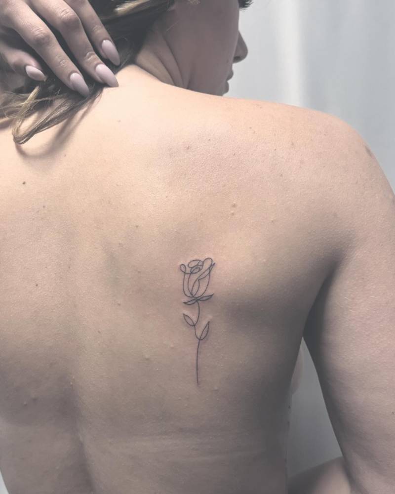 One line rose tattoo placed on the shoulder blade.