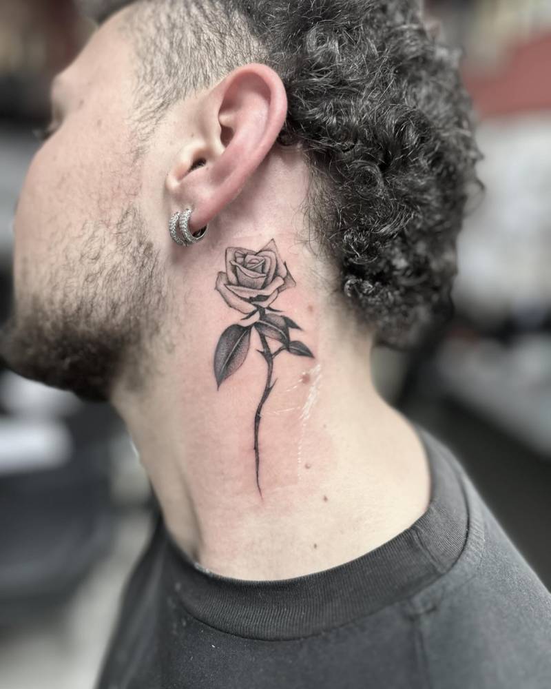 Rose tattoo in illustrative style located on the neck.